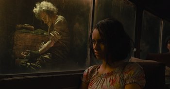 Movie still from “The Suicide Squad” (2021), directed by James Gunn – A woman standing in front of a painting of an old man; Medium shot, Low angle