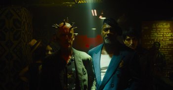 Movie still from “The Suicide Squad” (2021), directed by James Gunn – Two men in suits and hats are standing in a dark room; Medium shot, Low angle