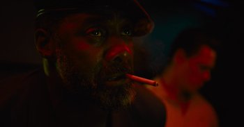 Movie still from “The Suicide Squad” (2021), directed by James Gunn – A man with a beard is smoking a cigarette; Close Up shot, High angle