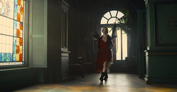 Movie still from “The Suicide Squad” (2021), directed by James Gunn – A woman in a red dress holding two black umbrellas; Wide shot, Low angle