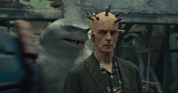 Movie still from “The Suicide Squad” (2021), directed by James Gunn – A bald man with a bunch of hairpins on his head; Close Up shot, Over the shoulder angle