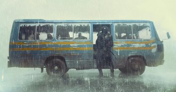 Movie still from “The Suicide Squad” (2021), directed by James Gunn – A man standing in front of a bus on a rainy day; Wide shot, Low angle