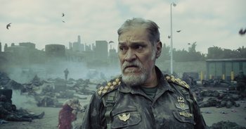 Movie still from “The Suicide Squad” (2021), directed by James Gunn – An older man in military fatigues stares into the camera; Close Up shot, Low angle