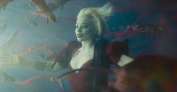 Movie still from “The Suicide Squad” (2021), directed by James Gunn – A woman with blonde hair and a red dress is underwater; Medium shot, High angle