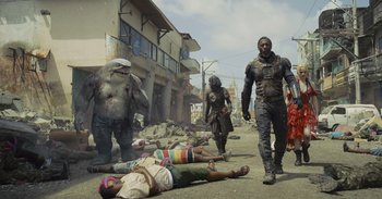 Movie still from “The Suicide Squad” (2021), directed by James Gunn – A group of people that are standing in the dirt; Wide shot, Low angle