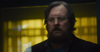 Movie still from “The Suicide Squad” (2021), directed by James Gunn – A man with a beard wearing glasses and a jacket; Close Up shot, Low angle