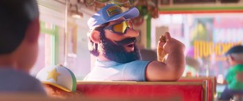 Movie still from “The Super Mario Bros. Movie” (2023), directed by Aaron Horvath – A man with a beard wearing a hat and sunglasses; Close Up shot, Low angle