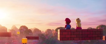 Movie still from “The Super Mario Bros. Movie” (2023), directed by Aaron Horvath – A person sitting on top of a brick wall in front of a sunset; Wide shot, Over the shoulder angle
