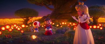 Movie still from “The Super Mario Bros. Movie” (2023), directed by Aaron Horvath – A group of people sitting in a field with lights in the background; Wide shot, Over the shoulder angle
