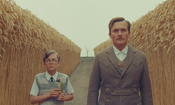 Movie still from “The Swan” (2023), directed by Wes Anderson – A man and a boy standing next to each other; Medium shot, Low angle