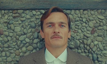 Movie still from “The Swan” (2023), directed by Wes Anderson – A person wearing a suit and tie; Close Up shot, Low angle