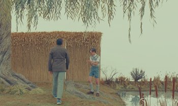 Movie still from “The Swan” (2023), directed by Wes Anderson – Two men standing on the side of a river; Wide shot, Over the shoulder angle