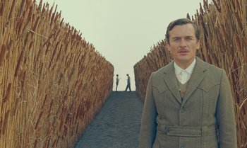 Movie still from “The Swan” (2023), directed by Wes Anderson – A man standing in front of two men on a path; Medium shot, Low angle