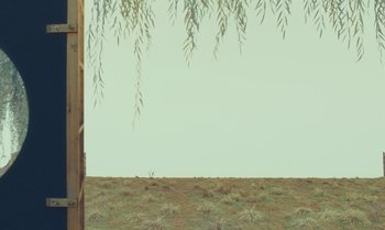 Movie still from “The Swan” (2023), directed by Wes Anderson – A field that has some grass on the ground; Extreme Wide shot, Low angle