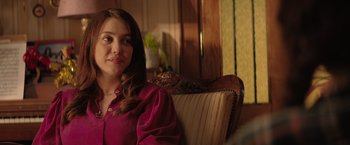 Movie still from “The Swimmers” (2022), directed by Sally El Hosaini – A woman sitting on top of a couch in a room; Close Up shot, Over the shoulder angle