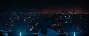 Movie still from “The Swimmers” (2022), directed by Sally El Hosaini – A woman looking out over a large city at night; Extreme Wide shot, High angle
