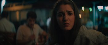 Movie still from “The Swimmers” (2022), directed by Sally El Hosaini – A young woman looking sad in front of a man in a bar; Close Up shot, Low angle