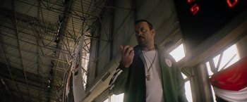 Movie still from “The Swimmers” (2022), directed by Sally El Hosaini – A man holding an object while standing in a building; Medium shot, Low angle