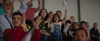 Movie still from “The Swimmers” (2022), directed by Sally El Hosaini – A group of people standing up and clapping hands; Medium shot, High angle