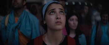 Movie still from “The Swimmers” (2022), directed by Sally El Hosaini – A woman looking up while standing in front of a group of people; Close Up shot, Low angle