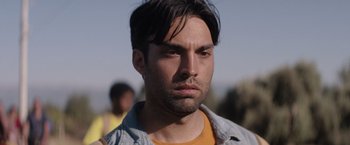 Movie still from “The Swimmers” (2022), directed by Sally El Hosaini – A person wearing a jean jacket; Close Up shot, Over the shoulder angle