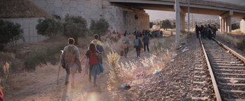 Movie still from “The Swimmers” (2022), directed by Sally El Hosaini – A group of people walking down a dirt road; Extreme Wide shot, High angle
