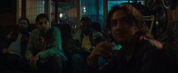 Movie still from “The Swimmers” (2022), directed by Sally El Hosaini – A group of people sitting on a bus at night; Medium shot, Low angle