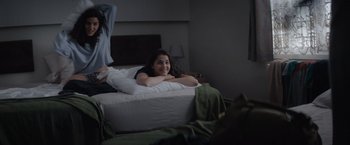 Movie still from “The Swimmers” (2022), directed by Sally El Hosaini – A woman laying on a bed smiling at the camera; Medium shot, Over the shoulder angle