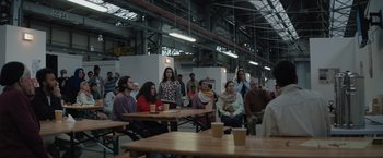 Movie still from “The Swimmers” (2022), directed by Sally El Hosaini – A group of people sitting at tables with drinks; Wide shot, Over the shoulder angle