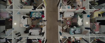 Movie still from “The Swimmers” (2022), directed by Sally El Hosaini – A room filled with lots of beds and a lot of clothes; Extreme Wide shot, Overhead angle