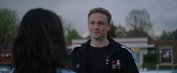 Movie still from “The Swimmers” (2022), directed by Sally El Hosaini – A man in a black jacket talking to a woman in a black jacket; Close Up shot, Over the shoulder angle