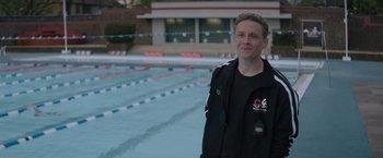 Movie still from “The Swimmers” (2022), directed by Sally El Hosaini – A man standing in front of an empty swimming pool; Medium shot, High angle