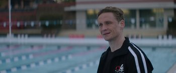 Movie still from “The Swimmers” (2022), directed by Sally El Hosaini – A man standing in front of a swimming pool; Close Up shot, Over the shoulder angle