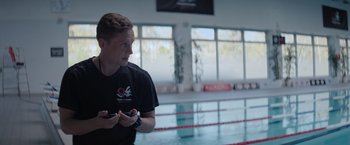 Movie still from “The Swimmers” (2022), directed by Sally El Hosaini – A man standing in front of a swimming pool; Close Up shot, Over the shoulder angle