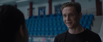 Movie still from “The Swimmers” (2022), directed by Sally El Hosaini – A man standing in front of an empty stadium; Close Up shot, Over the shoulder angle