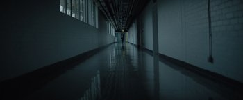 Movie still from “The Swimmers” (2022), directed by Sally El Hosaini – A person is walking down a hallway in a building; Extreme Wide shot, Low angle