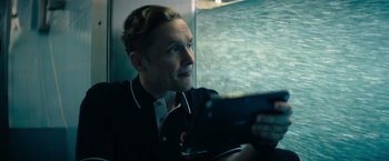 Movie still from “The Swimmers” (2022), directed by Sally El Hosaini – A man sitting in front of a window holding a tablet computer; Close Up shot, Low angle