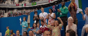 Movie still from “The Swimmers” (2022), directed by Sally El Hosaini – A group of people are sitting in the stands at a sporting event; Medium shot, Low angle