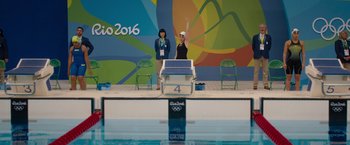 Movie still from “The Swimmers” (2022), directed by Sally El Hosaini – A table tennis player raises his hand in the air in front of a pool; Extreme Wide shot, High angle