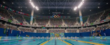 Movie still from “The Swimmers” (2022), directed by Sally El Hosaini – An olympic swimming pool in an olympic stadium; Extreme Wide shot, High angle