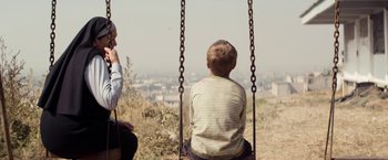 Movie still from “Elysium” (2013), directed by Neill Blomkamp – A man and a boy on a swing in a field; Medium shot, Over the shoulder angle