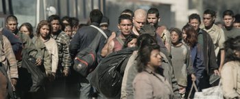 Movie still from “Elysium” (2013), directed by Neill Blomkamp – A large group of people walking down a street; Wide shot, Over the shoulder angle