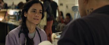 Movie still from “Elysium” (2013), directed by Neill Blomkamp – A female doctor is sitting in front of a group of people; Close Up shot, Over the shoulder angle