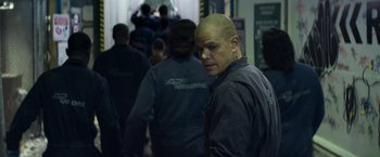 Movie still from “Elysium” (2013), directed by Neill Blomkamp – A man with a bald head and a crowd of people; Medium shot, Over the shoulder angle