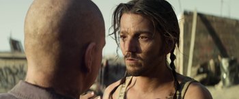 Movie still from “Elysium” (2013), directed by Neill Blomkamp – A person with long hair and a beard; Close Up shot, Over the shoulder angle