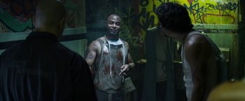 Movie still from “Elysium” (2013), directed by Neill Blomkamp – A man smoking a cigarette in a room with graffiti on the walls; Medium shot, Over the shoulder angle