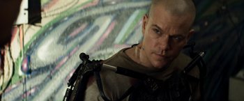 Movie still from “Elysium” (2013), directed by Neill Blomkamp – A man with a shaved head is holding a gun; Close Up shot, Low angle