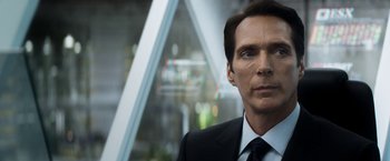 Movie still from “Elysium” (2013), directed by Neill Blomkamp – A man in a suit and tie standing in front of a building; Close Up shot, Low angle