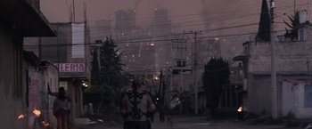 Movie still from “Elysium” (2013), directed by Neill Blomkamp – A person with a backpack walking down a street; Extreme Wide shot, Over the shoulder angle