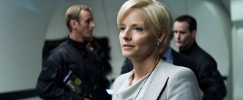 Movie still from “Elysium” (2013), directed by Neill Blomkamp – A woman with short blonde hair is looking into the distance; Close Up shot, Over the shoulder angle